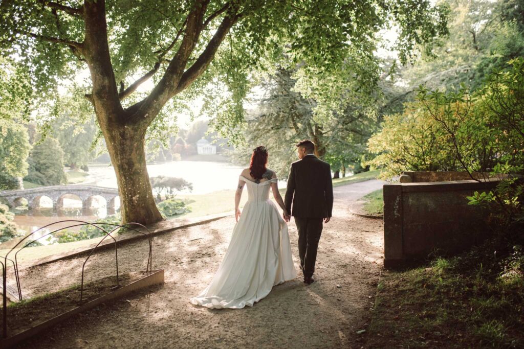 bride and groom walking under the trees at Stourhead Gardens in Wiltshire