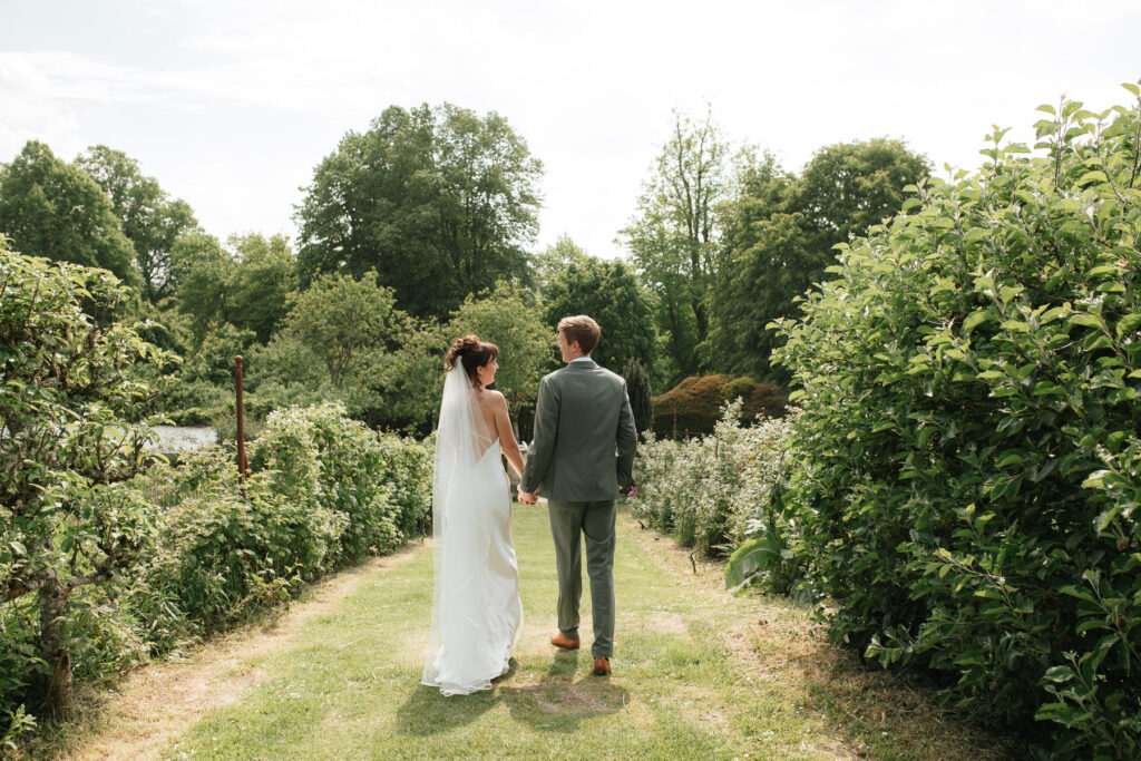 bride and groom walking hand in hand through the gardens at Pythouse Kitchen Garden, Wiltshire
