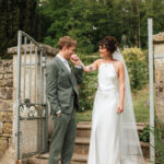 groom kissing his bride on her hand as he leads her down the steps at pythouse kitchen garden in Wiltshire