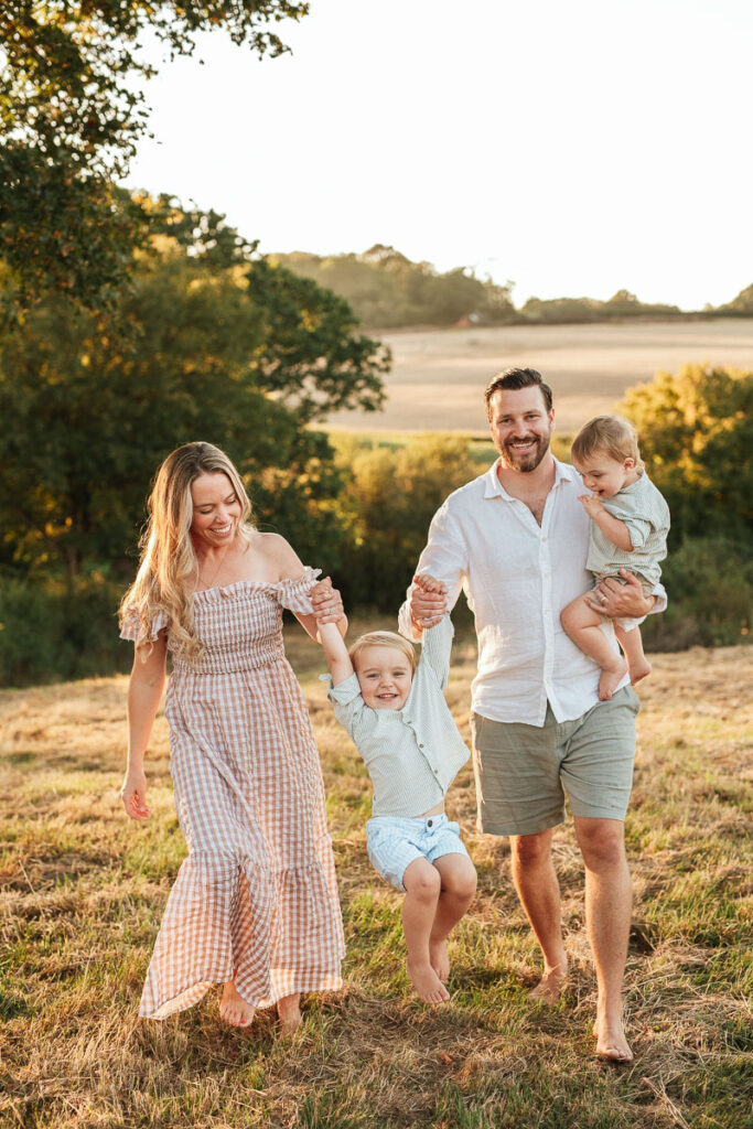 parents walking together with their two young children. They are swinging their boy in the air as they walk.