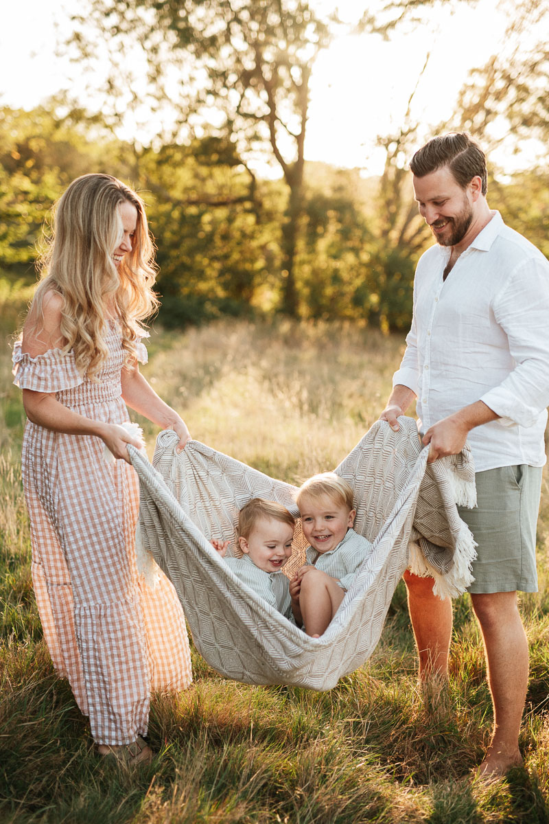 parents lifting their boys up in a blanket during a family photography session by Wiltshire photographer Rachel Jane