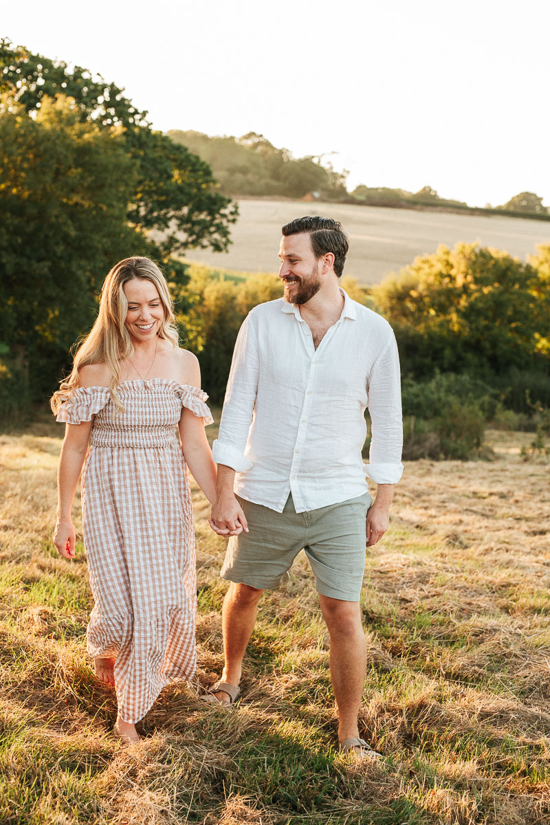newly engaged couple walking hand in hand during sunset 