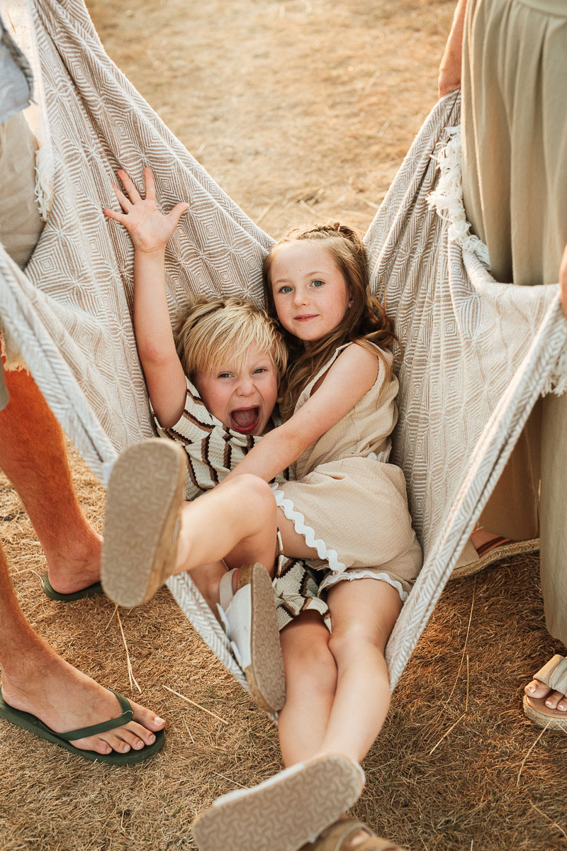 brother and sister being swung in a blanket during a sunset family photoshoot