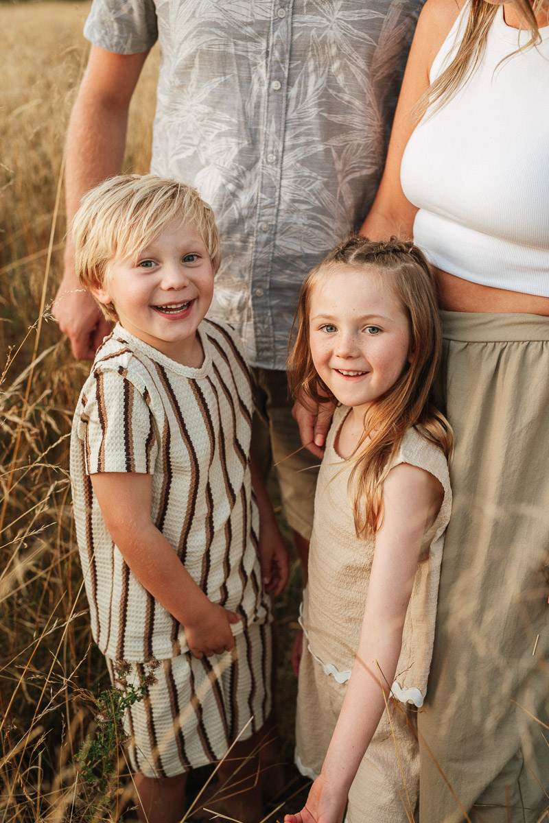 brother and sister standing at their mum and dads feet during sunset at tadpole garden village fields