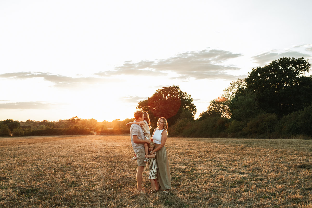 parents and 2 children standing together in a golden field in Tadpole Garden Village