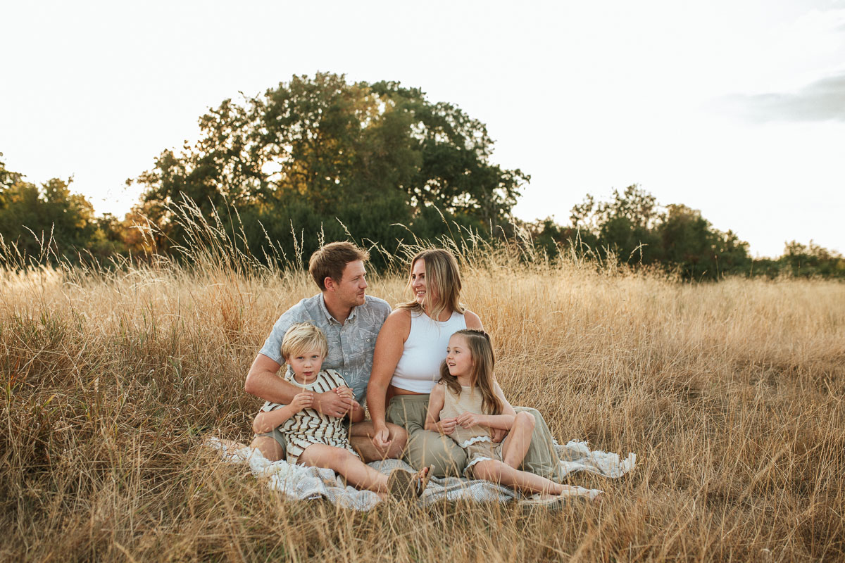 Family of four enjoying a relaxed outdoor moment together at sunset in Tadpole Garden Village.