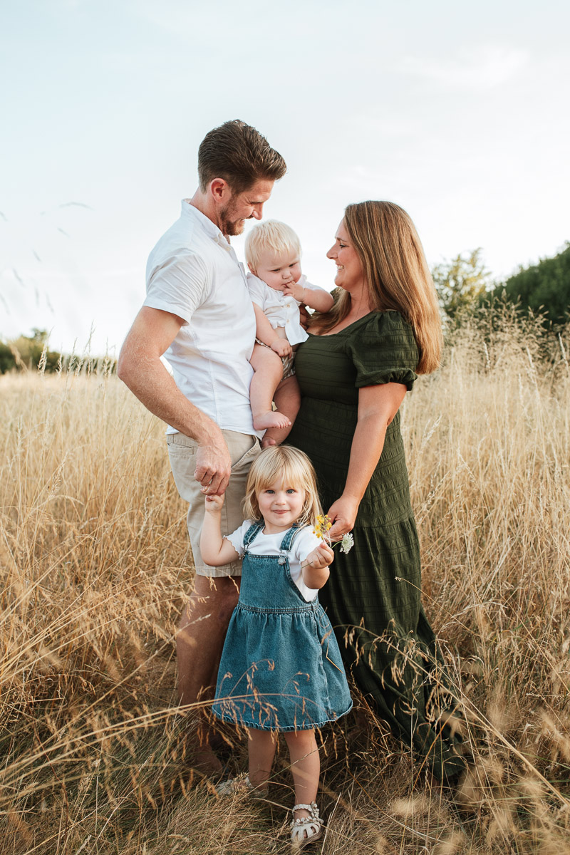 mum and dad holding their baby as their little one stands at the ir feet in the fields at tadpole garden village
