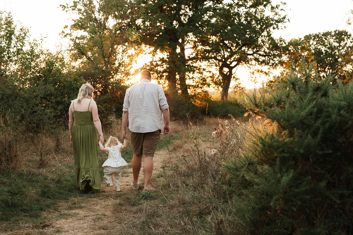 family of 3 walking hand in hand through the fields during sunset at tadpole garden village