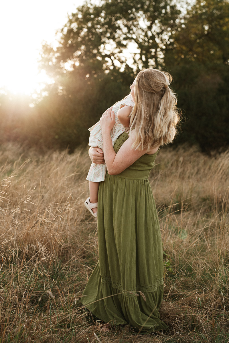 mother holding her daughter close for a cuddle during sunset at tadpole garden village swindon