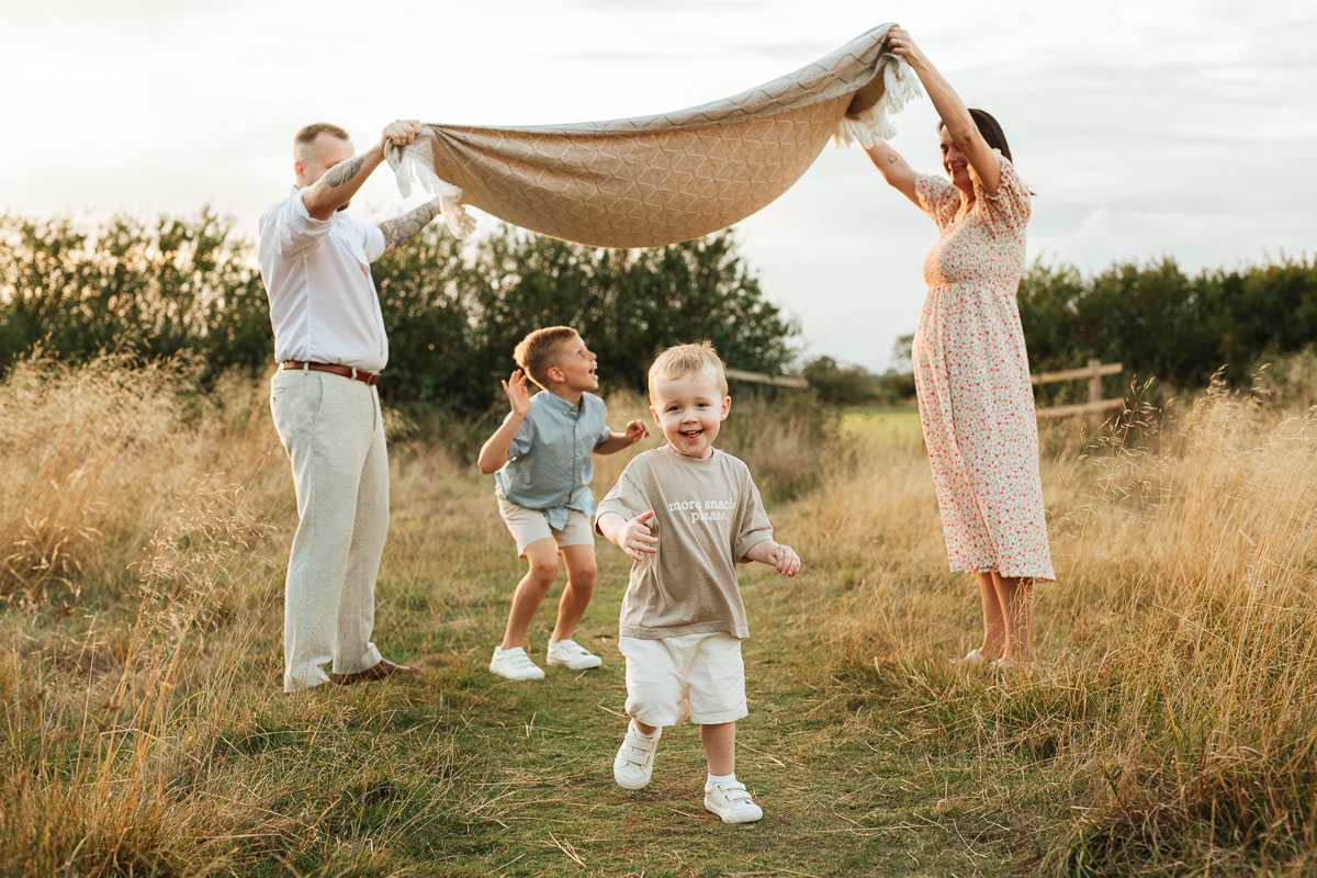 children running under a blanket as their parents hold it in the air
