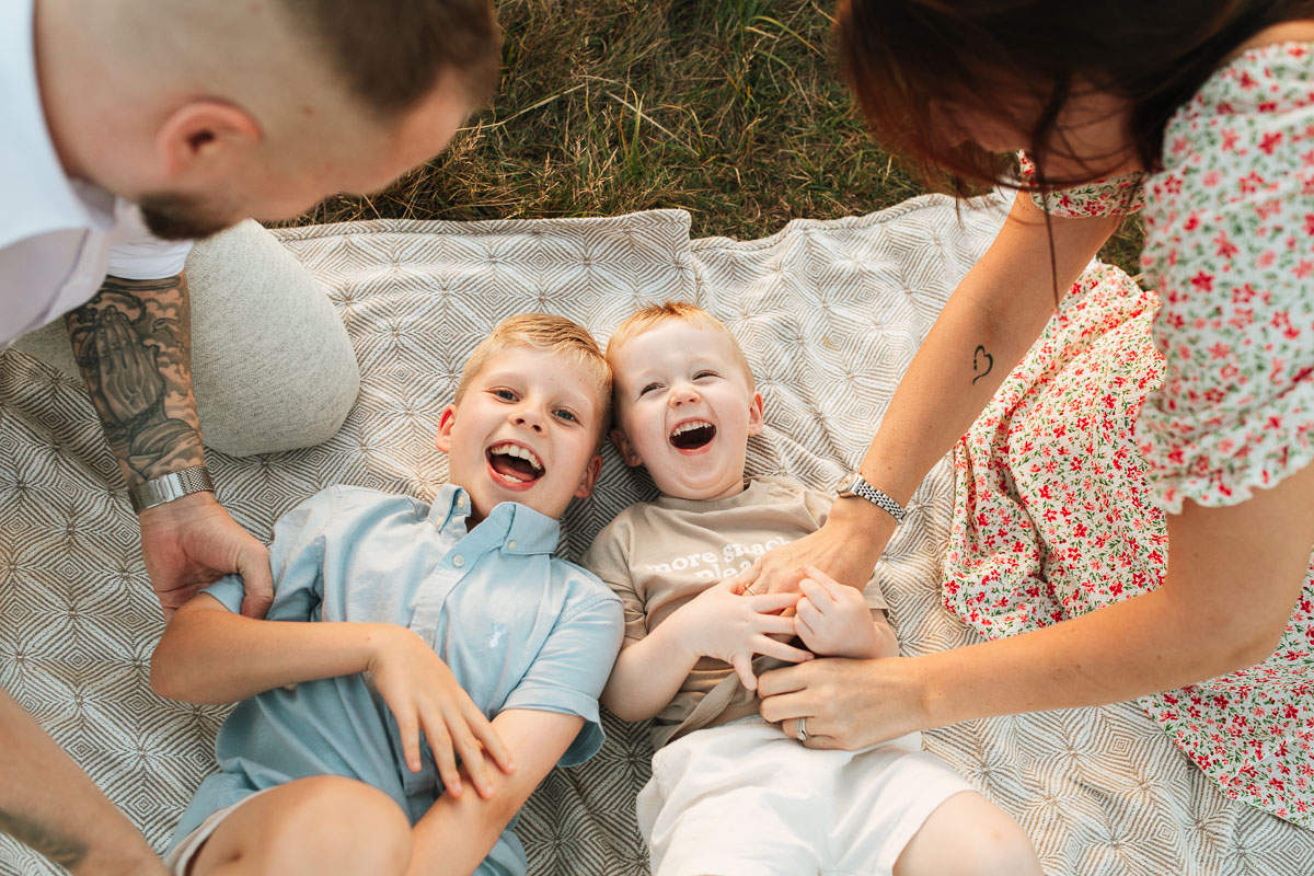 parents tickling their children on a blanket during their relaxed family photography session in tadpole garden village