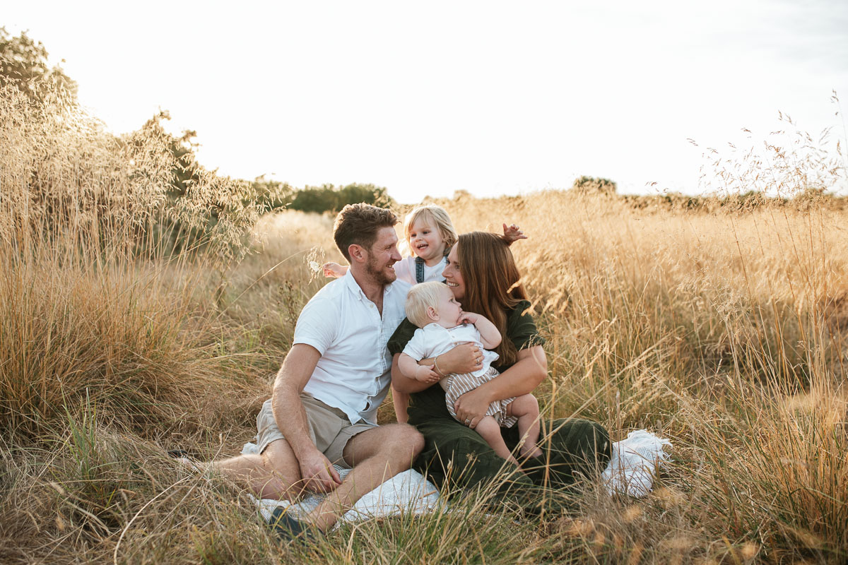 Family of four enjoying a relaxed outdoor moment together at sunset in Tadpole Garden Village.