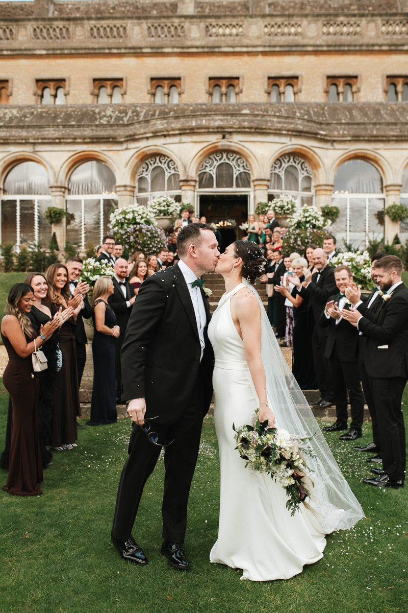 bride and groom share a kiss at the end of the confetti line
