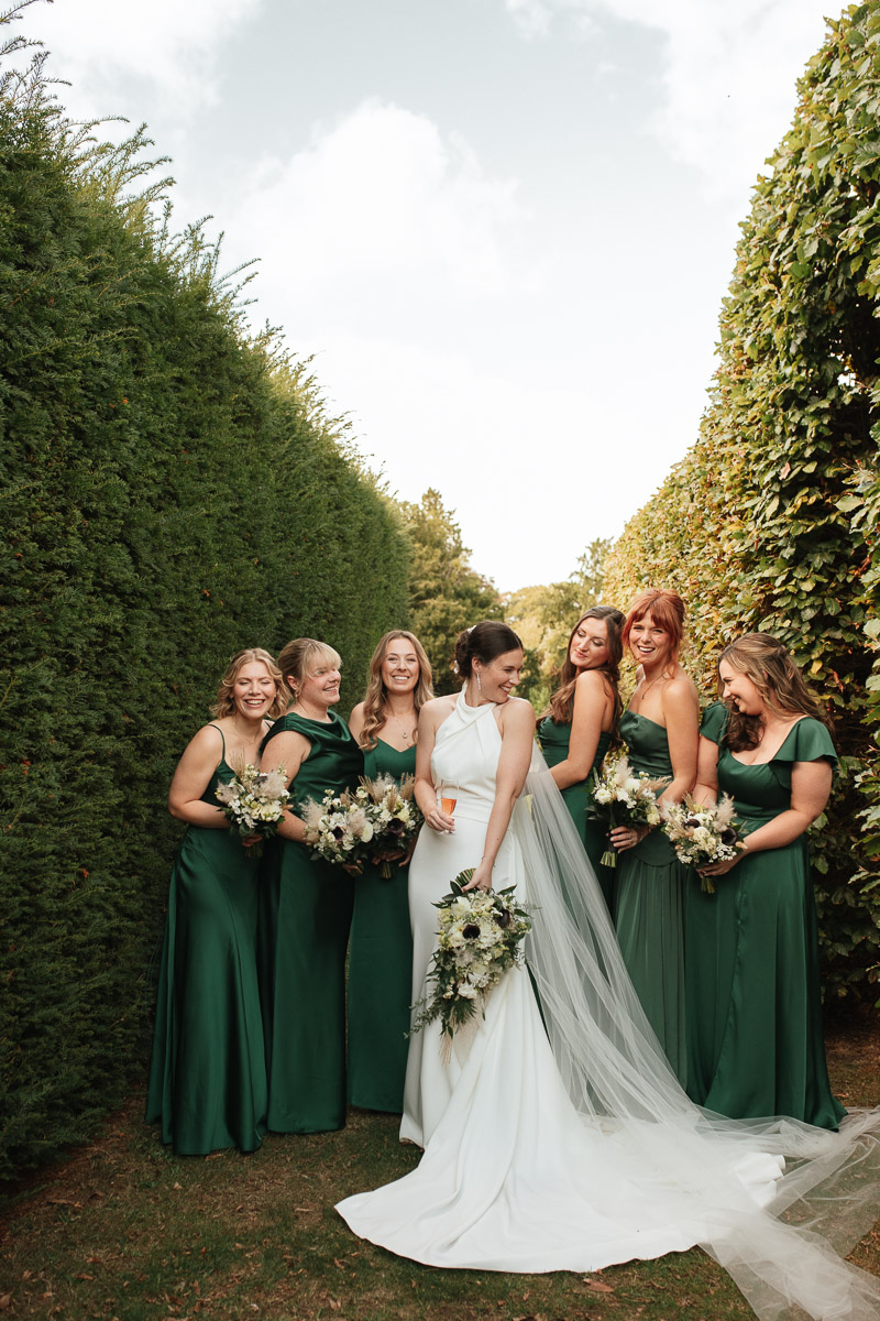 bride and her bridesmaids standing close together in the gardens at grittleton house