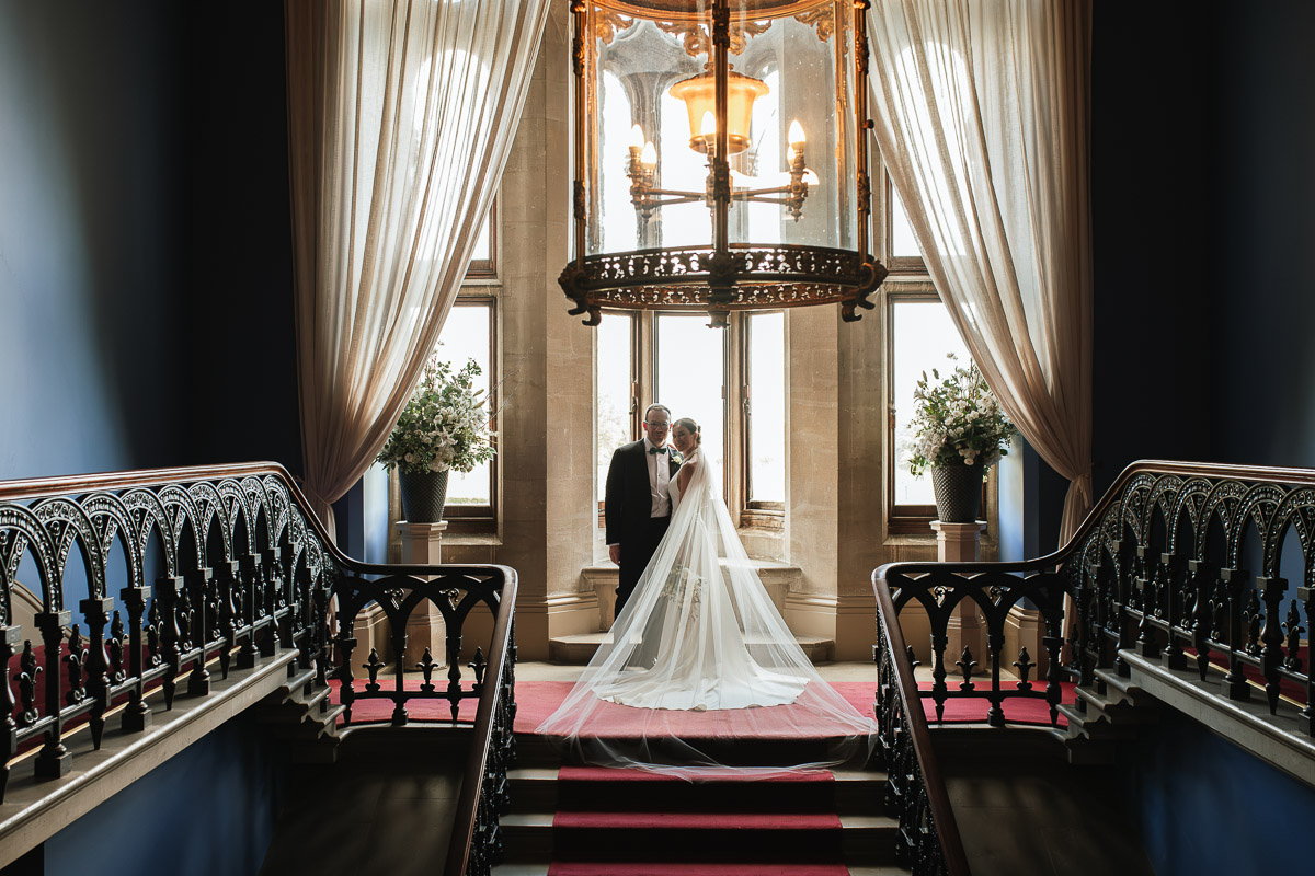 bride and groom standing at the top of the stairs inside grittleton house